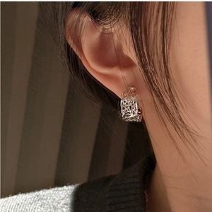 Close-up of 925 sterling silver earrings with irregular lava texture worn by a model