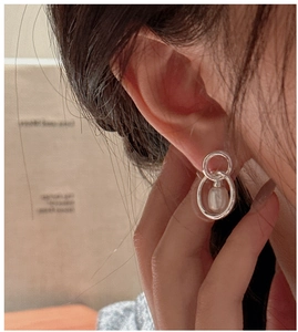 Macro shot of minimalist S925 silver double hoop earrings with teardrop pearl charm
