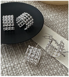 Dettaglio macro di orecchini a griglia 3D in argento con trama a rete stile minimalista