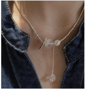 Detail of silver snowflake ghost necklace with frosted beads and tassels on denim