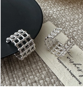 Detailed view of silver mesh textured earrings featuring an industrial grid pattern