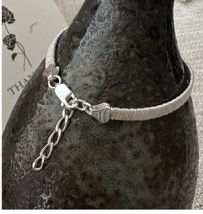 Detail of S925 sterling silver woven bracelet with lobster clasp and heart charm