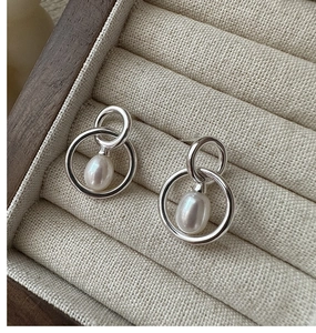 Close-up of S925 sterling silver interlocking rings with white teardrop pearl on velvet