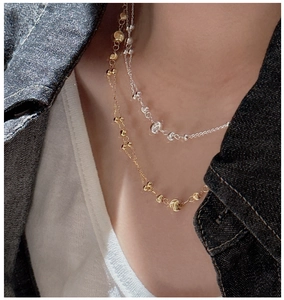 Close-up of gold and silver layered beaded chains on a model wearing a white t-shirt