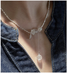 Macro shot of silver Y-shaped necklace with translucent crystal bead on denim background