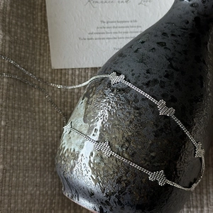 Elegant S925 sterling silver heart chain necklace displayed on a textured black vase