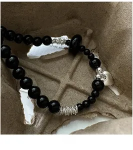 Macro shot of S925 silver heart charm and black onyx beads on a vintage beaded bracelet