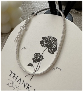 Close-up of S925 sterling silver woven bracelet with lobster clasp on a thank you card