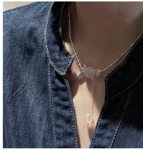 Detail of S925 sterling silver necklace with crystal beads and long tassel on denim shirt