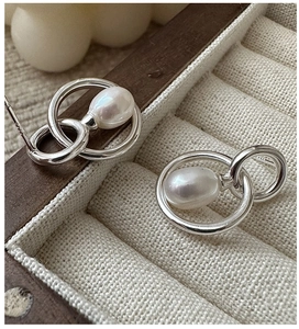 Macro shot of S925 silver vintage drop pearl earrings resting on beige linen jewelry tray