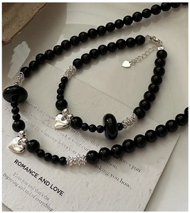 Detail of S925 silver black onyx beaded necklace set with heart charms on art card