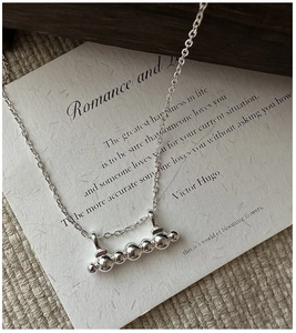 Macro shot of polished silver spheres on O-chain necklace with minimalist aesthetic