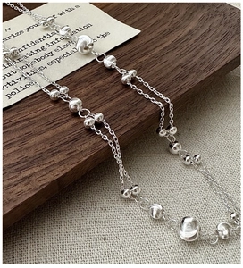 Macro shot of double-layered S925 silver cat-eye beaded necklace on a textured background