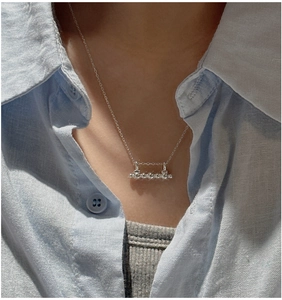 Detail of S925 sterling silver bar necklace with beads on model wearing blue linen shirt