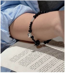 Detail of S925 silver heart charm on black onyx beaded bracelet worn on wrist