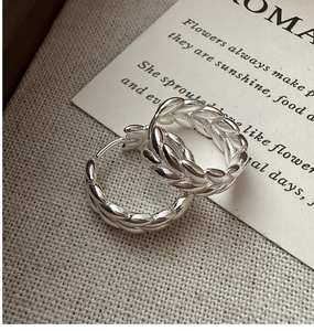 Macro detail of S925 silver hoop earrings with vintage wheat texture on canvas