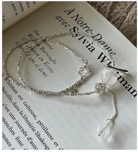 Macro shot of S925 silver snowflake necklace with transparent beads on French book pages