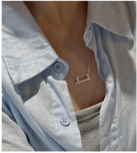 Detail shot of a minimalist S925 sterling silver necklace with a script pendant on model