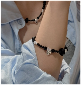 Close-up of S925 silver heart charm and black agate beads on a model's wrist