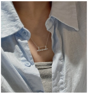 Detail view of S925 sterling silver bar necklace with five beads on a model's neck