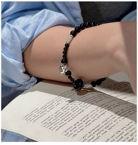 Close-up of S925 silver heart charm and black onyx beaded bracelet on model wrist