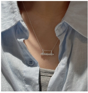 Close-up of a minimalist silver bar pendant necklace with five spheres worn on a neck