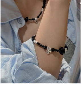 Detailed shot of black onyx beaded bracelet and necklace set with silver heart charms