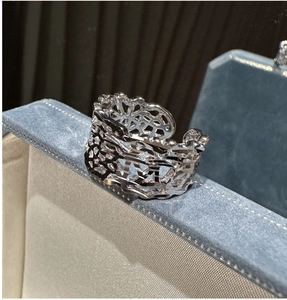 Macro shot of silver hollow mesh ring showing intricate CNC texture on jewelry box