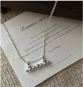 Macro detail of S925 sterling silver bar necklace with five polished silver beads