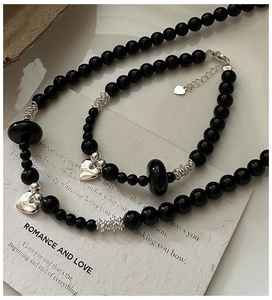 Detail shot of black onyx bead necklace and bracelet set with silver heart charms