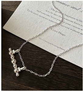 Detail of S925 silver horizontal bar necklace with beads on dark wood background