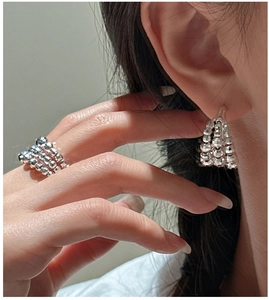 Detail view of silver S925 beaded layered earrings and matching ring with faceted texture