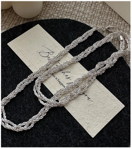 Detail of woven silver necklace with a lobster clasp on an elegant gift card