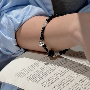 S925 sterling silver heart charm beaded bracelet with black onyx beads worn over a book