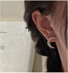 Close-up of minimalist silver crescent moon stud earrings worn for a sleek modern style