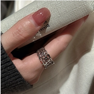 Macro detail of S925 sterling silver hollow chain ring worn on finger with a soft background