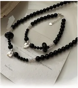 Detailed view of vintage black beaded necklace featuring a silver heart-shaped pendant detail