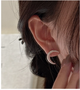 Close-up of S925 sterling silver crescent hoop earrings worn on ear with matte finish