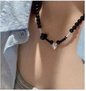 Detail of vintage black beaded necklace featuring a silver heart pendant on a model