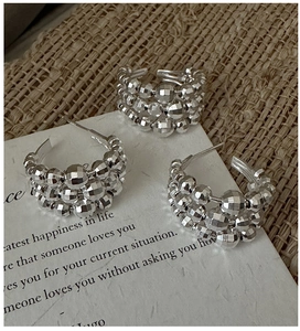 Macro detail of silver faceted beaded earrings on vintage rustic fabric background