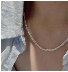 Detail of S925 sterling silver woven snowflake chain necklace on a model's collarbone