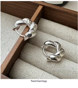 Detail shot of S925 sterling silver twisted hoop earrings on a beige linen jewelry display