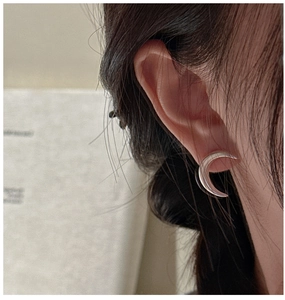 Close-up of minimalist S925 sterling silver crescent stud earrings on a model's ear