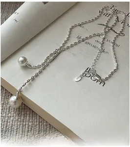 Detail of S925 sterling silver stamp on long pearl tassel Y-necklace over a book