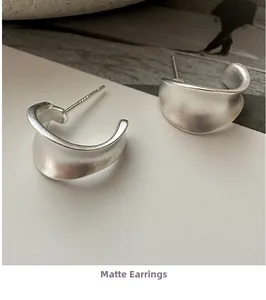 Detailed macro shot of matte 925 sterling silver C-shaped earrings with a textured finish