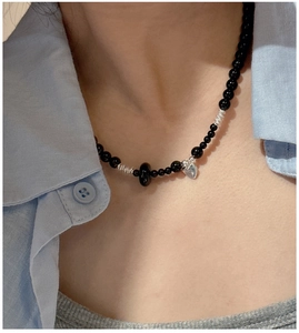 Detail of S925 silver black agate heart necklace worn with casual stylish outfit