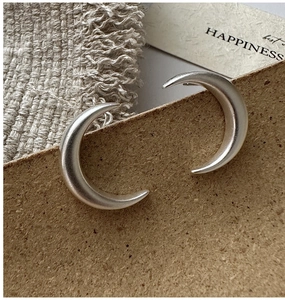 Macro detail of crescent moon stud earrings with a matte brushed silver finish