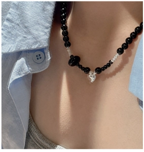 Macro shot of black beaded necklace with silver wire accents and clear heart pendant