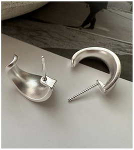 Macro detail of minimalist 925 sterling silver C-shaped earrings with matte brushed finish