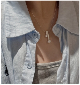 Détail du pendentif allumette en argent avec perles blanches sur une chaîne maille